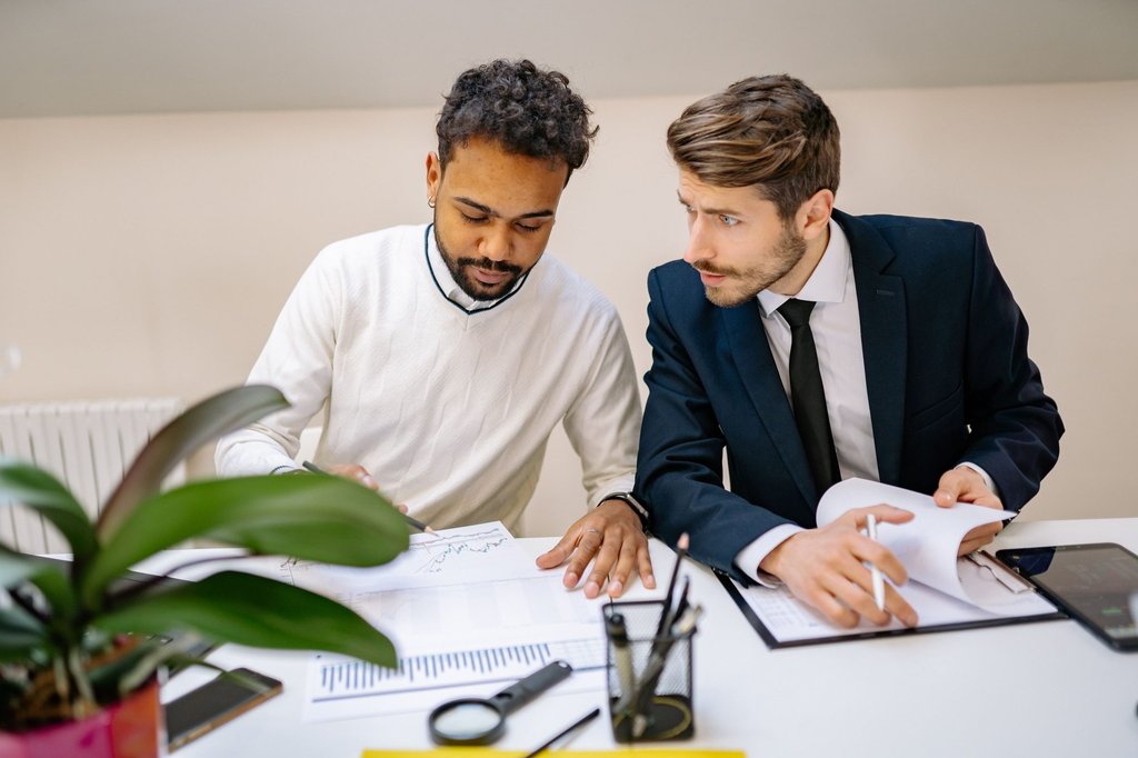 Two people reviewing printed pipeline charts and deal documents together at a table.