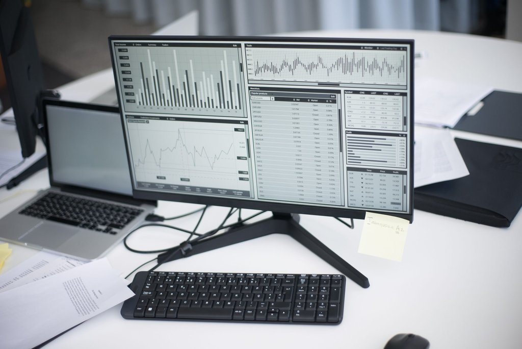 A workspace with analytical charts on a monitor, the kind of reporting view a managed Zoho Analytics setup produces.