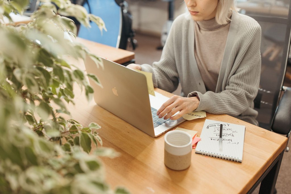 A woman working through her inbox on a laptop in a bright office.