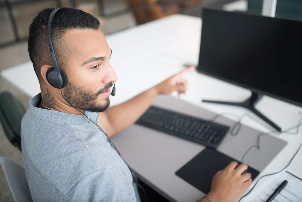 A support agent wearing a headset working through a customer issue at a service desk.