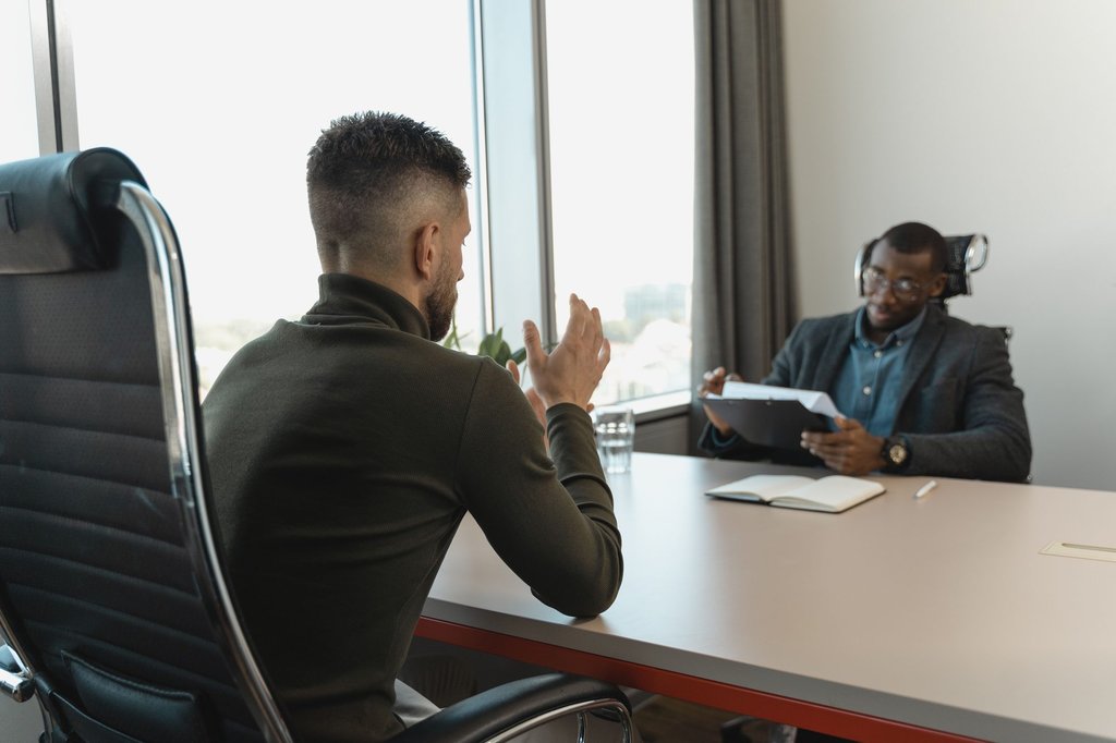 A job interview across a table in a bright office, the hiring stage Zoho Recruit keeps organised.