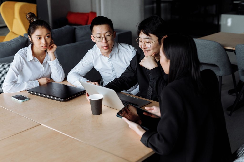 Colleagues in a team meeting around a laptop, working through a staffing discussion.
